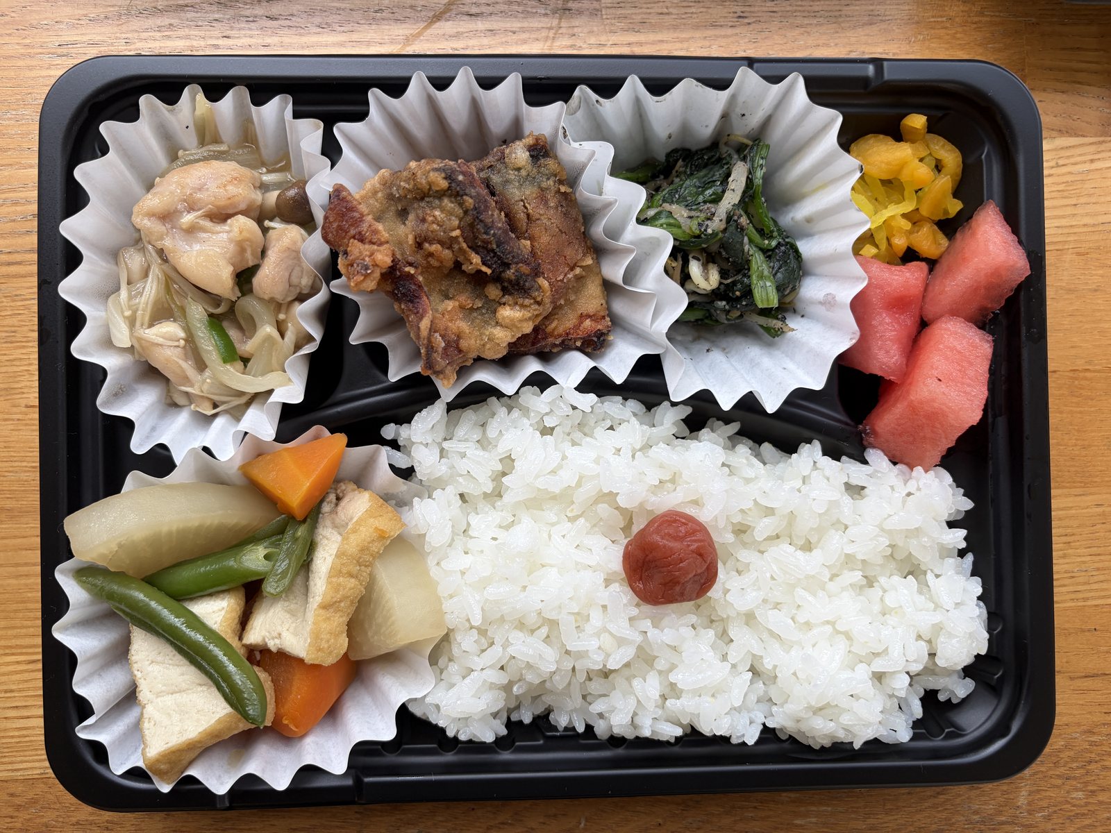 ご飯と主菜、野菜の煮物、果物を詰めたお弁当
